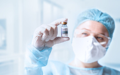 Obraz premium NO LOGOS OR TRADEMARKS! SELF MADE LABELS! Close up view of doctor with an ampule of covid vaccine on blue back