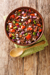 Azifa is an Ethiopian green lentil dish with lime juice, tomato, mild hot peppers, onion and spices close up in the plate on the table. Vertical top view from above