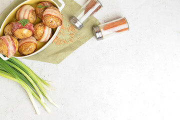Baking dish of tasty baked potatoes with bacon on white background