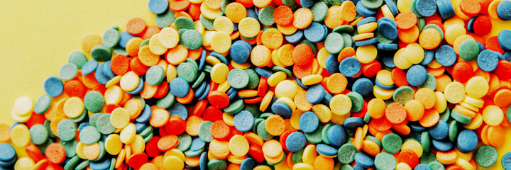 Colorful candies are neatly scattered on a yellow background