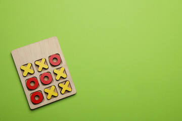 Tic tac toe set on light green background, top view. Space for text