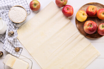 Fresh dough and ingredients for apple strudel on white wooden background