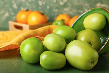 Bowl with fresh green tomatoes on table