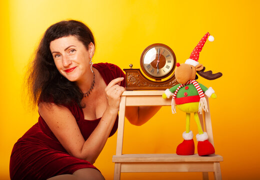 A Woman Of 50 Years Old On The Holiday New Year And Christmas Sits In The Background Of The Studio With A Clock Chime Chimes 2022