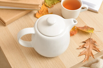 Tea pot and autumn leaves on table
