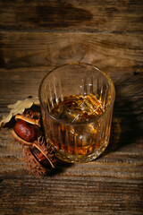 Glass of chestnut whiskey on wooden background