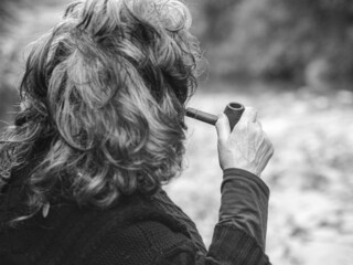 senior woman smoking pipe and relaxing outdoors in a pond in autumn