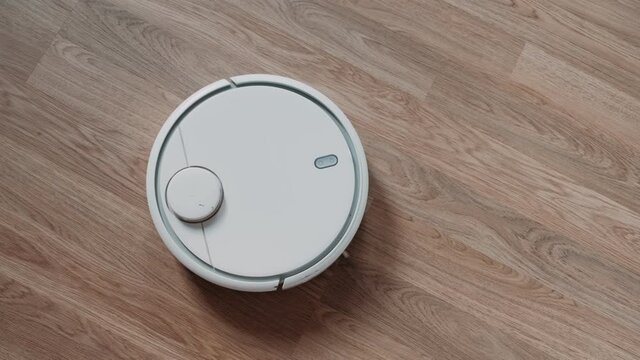 Smart Robot Vacuum Cleaner with lidar on wood floor. Robot vacuum cleaner performs automatic cleaning of the apartment. Smart Home.