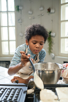African little boy learning to bake waffles on waffles icon in the kitchen