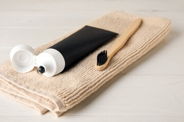 Black toothpaste with activated carbon, brush and towel on table