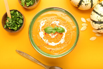 Bowl with tasty pumpkin cream soup on orange background