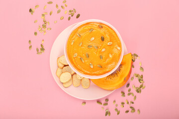 Bowl with delicious pumpkin cream soup and croutons on pink background
