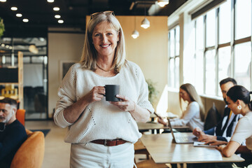 Smiling mature businesswoman standing in a co-working space