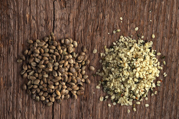 Raw hemp seeds, whole and shelled on a rough woody texture background. Selective focus.