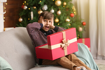 Fototapeta na wymiar Surprised little boy opening Christmas gift at home
