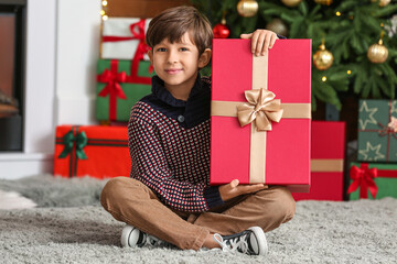 Obraz na płótnie Canvas Cute little boy with gift at home on Christmas eve
