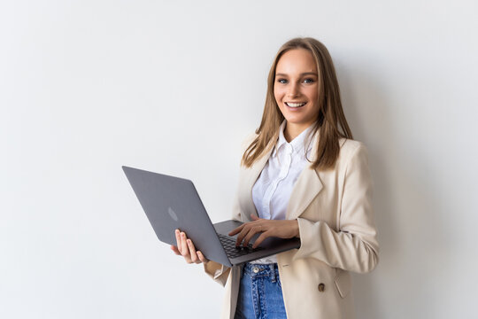Portrait of young businesswoman holding laptop in the office isolated over white background