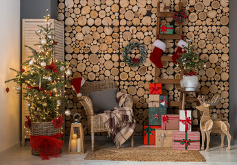 Christmas trees with armchair, ladder and gifts near wooden wall