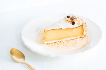 French flan on white plate with biscuit crumbs around, with almonds on top. Piece of cake on white bright background, traditional french  dessert