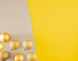 three golden baubles gainst grey and yellow illuminating background with copy space. modern christmas surrealism background with copy space.