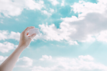 Hands holding clouds in the sky.