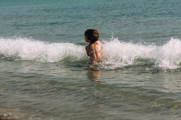 Boy plays with waves in the sea.