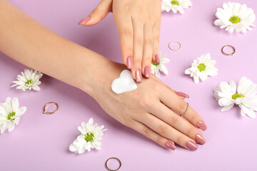 Concept of hand care on purple background with flowers