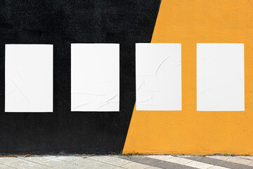 Modern urban street scene with colorful geometrical wall and four white glued wrinkled poster...