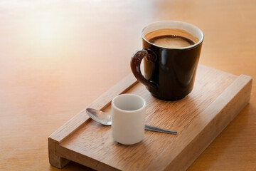Hot black coffee in black mug with brown sugar in white small cup and small spoon on a wood tray at a restaurant  or coffee shop, morning breakfast for most of the officers in a hurry hour