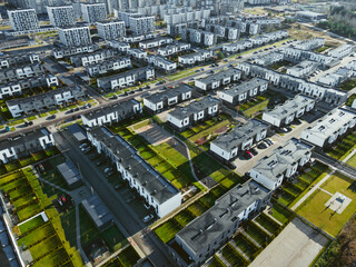 Aerial photo of the modern residential district in growing europe city. Block flats and cottages with yards and greenery. City expansion, capitalism. 
