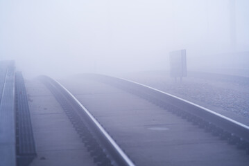 Fototapeta na wymiar Railway tracks at train station with sea of fog in the background on a foggy autumn day. Photo taken November 19th, 2021, Zurich, Switzerland.
