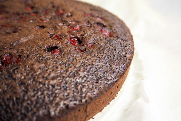 vegan chocolate cake with red currant lies on white parchment paper. side view. gluten-free pastries. lactose-free