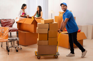 Girls busy with packing while the delivery boy moving boxes to new house
