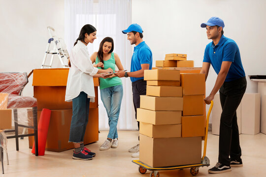 Adult girls checking list of carton boxes with delivery boys before delivery