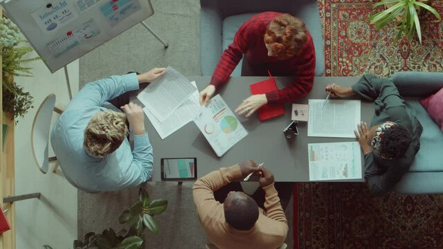 Time lapse top down shot of team of multiethnic colleagues working on business project at office meeting