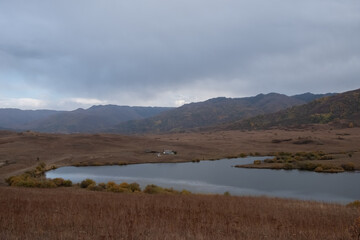 Beautiful lake in the mountains with mountains and clouds reflections on water.