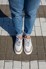 Men's feet in white everyday sneakers made of natural leather on lacing.