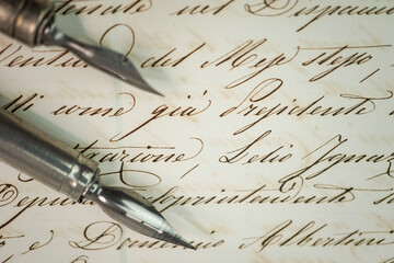 Top view close-up of a pair of calligraphy nibs over a manuscript 