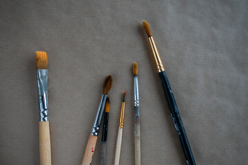 Six brushes are lying on craft paper. Devices for drawing. selective focus.