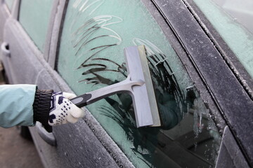 Frosted car side door window cleaning from a hoar frost before a drive at frozen winter day -...