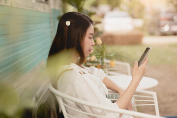 Asian lady sitting outdoor relax looking at smartphone feel leisure in holiday