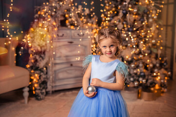 Fototapeta na wymiar beautiful girl in an elegant dress against the background of Christmas lights and a Christmas tree in a beautiful interior