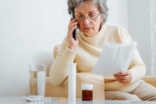 Mature sick woman patient consultation with doctor by phone, prescription for dosage of treatment at home. Senior woman talking on smartphone with doctor, sitting on chair with medicine instruction