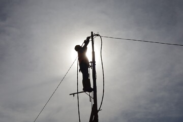 an electrician climbs a power pole to connect electrical wires to make a new electrical connection