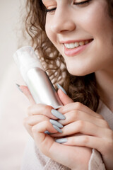 Concept of care for skin face and structure of hair young woman, closeup smile and bottle with liquid bubble product