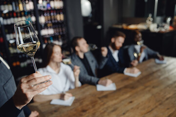 Closeup hand of Professional sommelier conducts white wine tasting for business company in restaurant