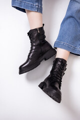 Beautiful female legs with fashionable black boots on the background in the studio. Women's stylish leather boots.
