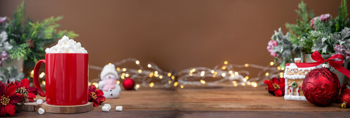 Red mug with hot chocolate and marshmallows with Christmas decoration on background, bokeh lights and copy space