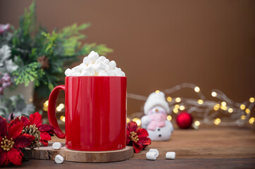 Red mug with hot chocolate, marshmallows. Christmas decoration on wooden background, copy space