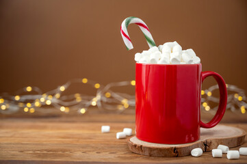 Hot chocolate or warm winter drink in red mug with marshmallows. Christmas concept, bokeh lights